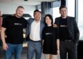 Tres hombres y una mujer con franelas negras con el logo de Bybit EU esperando la foto.