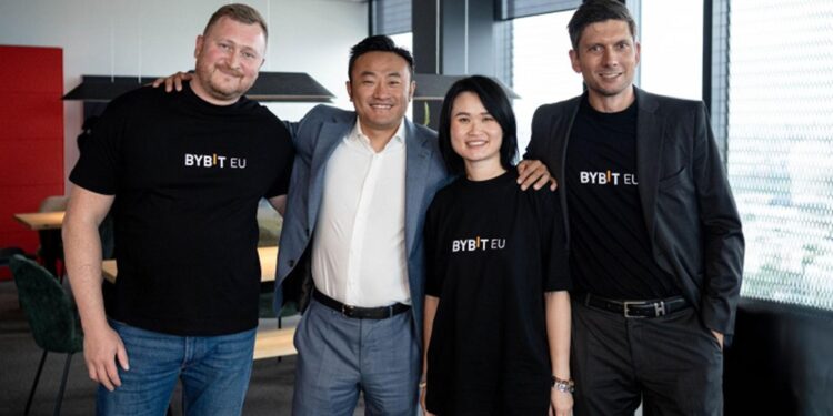 Tres hombres y una mujer con franelas negras con el logo de Bybit EU esperando la foto.