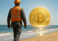 Un minero caminando en un playa con una moneda de BTC en el cielo.