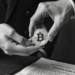 Una persona sosteniendo una moneda de bitcoin en sus manos con una orden 6201 en una mesa.