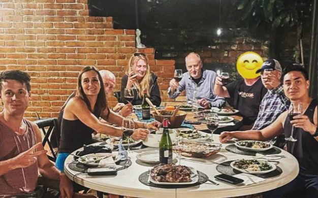 Varias personas sentadas en una mesa brindando, listos para el almuerzo en The Whale Lounge de Bitcoin Berlín en El Salvador.