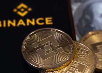teléfono con el logo de Binance y una moneda de BNB.
