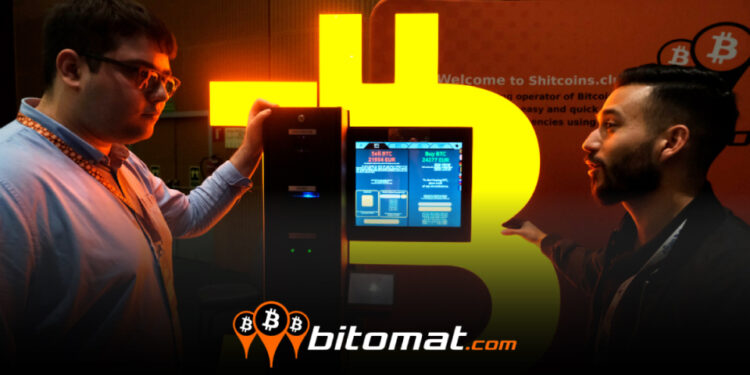 dos hombres conversando junto a minero de bitcoin encendido con logo de bitomat superpuesto