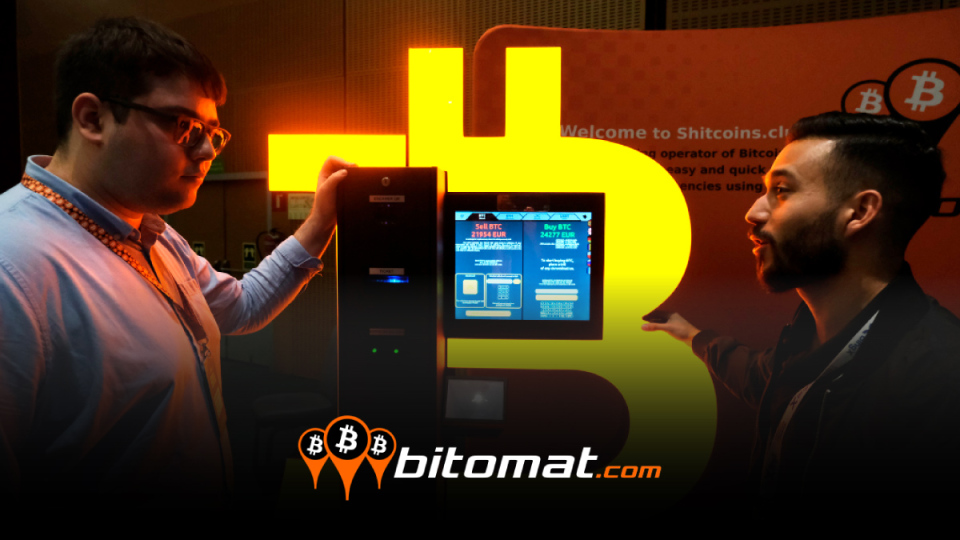 dos hombres conversando junto a minero de bitcoin encendido con logo de bitomat superpuesto
