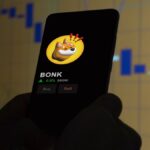 Un teléfono en el que se ve el logo de la criptomoneda BONK.