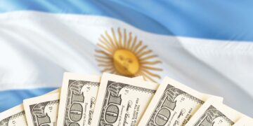 Dólares estadounidenses junto a la bandera de Argentina.