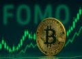 Bitcoin con gráficas en verde y la palabra FOMO en el fondo.