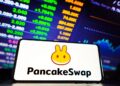 teléfono móvil con el logo de PancakeSwap y gráficos de fondos.
