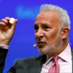 Peter Schiff aparace dando una conferencia y sostiene con su mano derecha una moneda física.