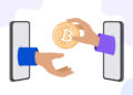 Una mano, que sale de la pantalla de un teléfono celular, entrega un bitcoin a otra que también sale de un teléfono.