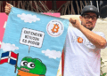 Pedro Vital muestra un pendón con el logo de Bitcoin Dominicana. Dominicana