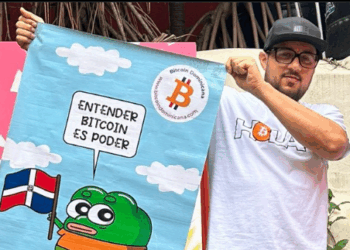 Pedro Vital muestra un pendón con el logo de Bitcoin Dominicana. Dominicana