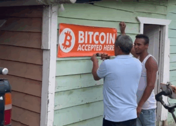 Dos personas colocan un aviso de "se acepta bitcoin" a las afueras de un comercio en República Dominicana.