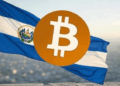 Una bandera de El Salvador con una moneda de Bitcoin en primer plano.