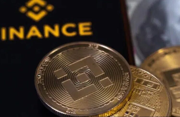 Monedas físicas de BNB con un teléfono móvil en el que se ve el logotipo del exchange Binance.