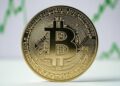 Bitcoin con gráficas verdes de fondo.
