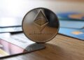Una moneda dorada de Ethereum junto a tarjetas de credito.