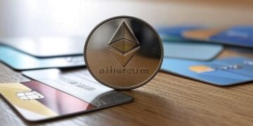 Una moneda dorada de Ethereum junto a tarjetas de credito.