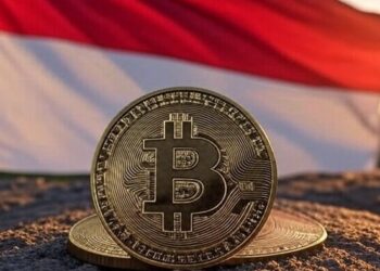 La bandera de Indonesia junto a una moneda dorada de bitcoin.