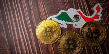 Mapa con bandera de México y monedas de bitcoin sobre una mesa.