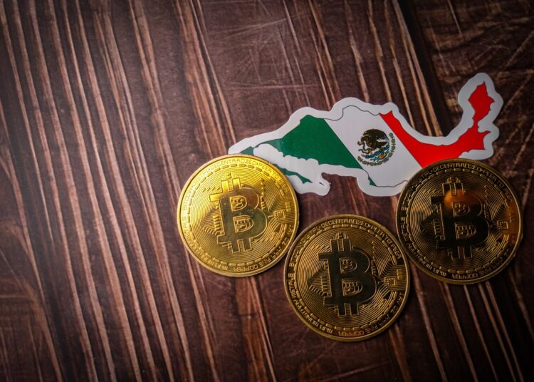 Mapa con bandera de México y monedas de bitcoin sobre una mesa.