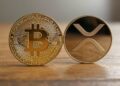 Una moneda dorada de bitcoin junto a una de XRP.