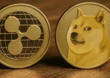 Monedas físicas de XRP y dogecoin (DOGE) arriba de una mesa.