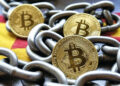 Monedas de Bitcoin encadenadas, sobre la bandera de España.