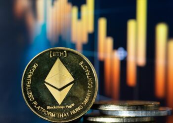 Una moneda de ETH con un gráfico al fondo.