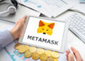 Una persona con una tablet en sus manos. En la pantalla se ve el logo de Metamask