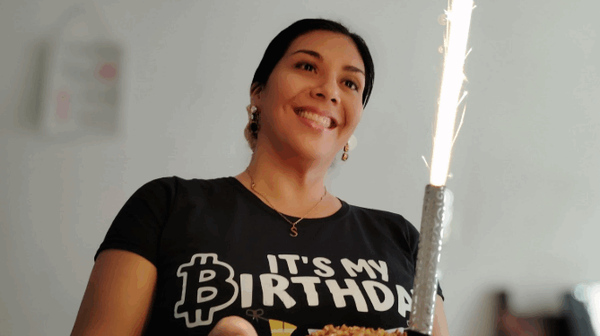 Una mujer luce una camiseta con el logo de bitcoin.