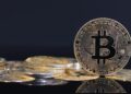 Una moneda de bitcoin está sobre una mesa.