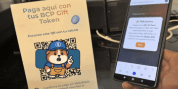 Un teléfono y un aviso que muestra el sistema de pago con criptomonedas del BCP.