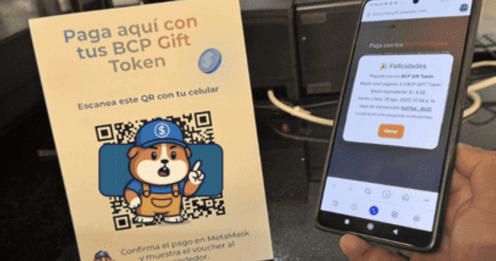Un teléfono y un aviso que muestra el sistema de pago con criptomonedas del BCP.