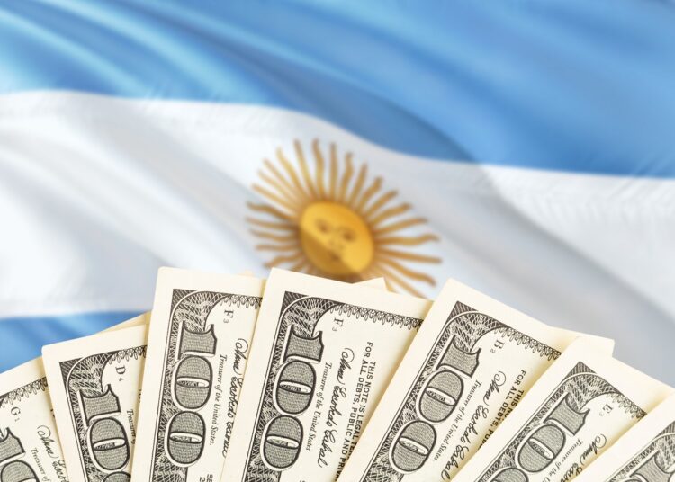 Dólares estadounidenses delante de la bandera de Argentina