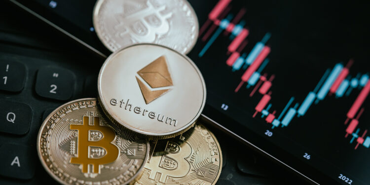 moneda de ethereum sobre monedas de bitcoin junto a pantalla con grafico de precio