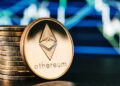 moneda de ethereum apoyada en monedas apiladas con grafico en el fondo