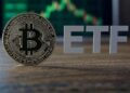 Moneda de bitcoin con las letras ETF al lado y gráfico de fondo.