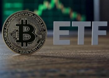 Moneda de bitcoin con las letras ETF al lado y gráfico de fondo.