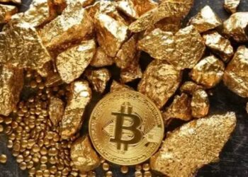 Pedazos de oro con una moneda de bitcoin sobre una mesa.