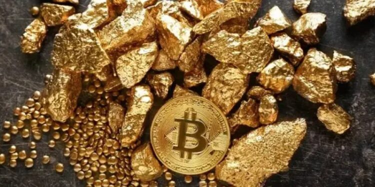 Pedazos de oro con una moneda de bitcoin sobre una mesa.