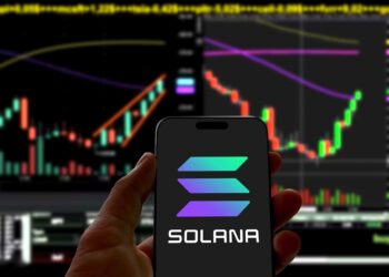 Logo de solana en un teléfono móvil y gráfico de precio genérico.