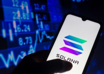 Una mano sosteniendo un teléfono con el logo de solana.