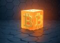 Un bloque brillante con dos logos "B" de Bitcoin. De fondo, una estructura de colo negro, similar a un panal de abejas.
