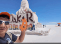 Una persona sostiene en alto un logo color naranja de bitcoin en las salinas de Bolivia.