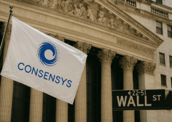 Bandera blanca con el logotipo azul de ConsenSys ondeando frente a la fachada del edificio de la Bolsa de Nueva York en Wall Street, junto al letrero negro característico de “WALL ST”.