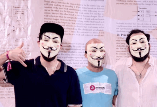 3 jovenes lucen máscara de Anonymous frente a pendón del Libro Blanco de Bitcoin.