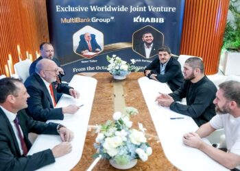 Grupo de hombres de negocio sentados alrededor de una mesa conversando.