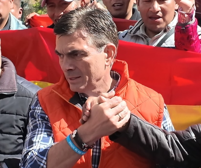 A photo of the elected president of Bolivia Rodrigo Paz Pereira, surrounded by people and shaking hands with one of them.