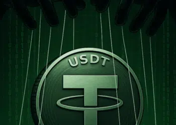 Logo de USDT impreso en una moneda física, en un fondo de color verde oscuro.